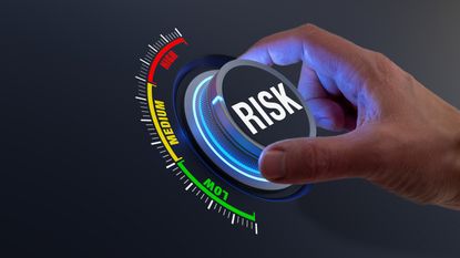 A man's hand turns a dial labeled risk.