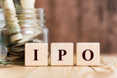 IPO written on wooden blocks with jar of money behind the blocks