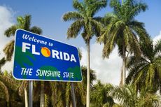 Welcome to Florida sign with palm trees in the background. 