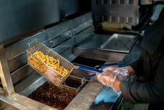 A person flips fries in a fryer.