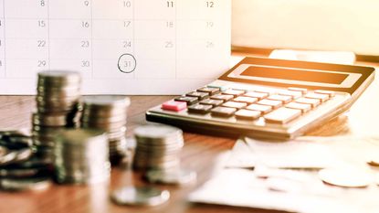 stacks of coins in front of calculator and calendar