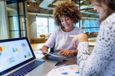 two women at work looking over financial charts