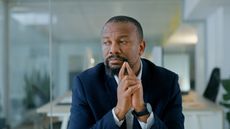 A man sits at his desk in an office trying to make an important decision.